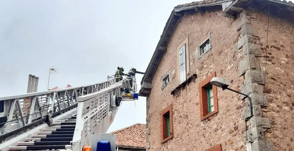 Los bomberos emplean la autoescala para evitar el desprendimiento de tejas en un edificio de Reinosa