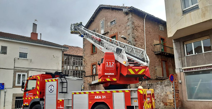 Los bomberos emplean la autoescala para evitar el desprendimiento de tejas en un edificio de Reinosa