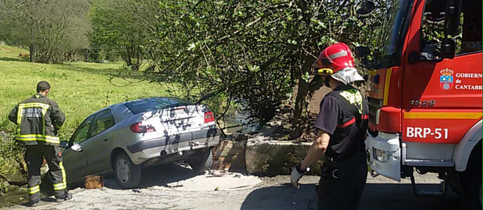 Los bomberos liberan a un hombre atrapado entre su vehculo y una roca del cauce de un riachuelo