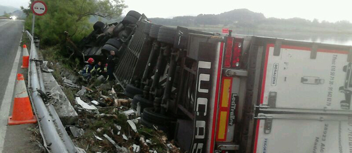 Los bomberos trasvasan el combustible de un camin volcado para evitar que llegue a la Ra de Argoos